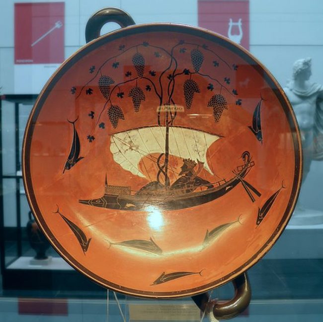 Exekias[4] tarafından boyanan siyah figürlü ünlü bir kylix[5]. Şarap tanrısı Dionysos bir gemide tasvir ediyor. Bir efsanede korsanların onu kaçırmak istediği ancak Dionysos’un hepsini yunuslara çevirdiği ve gemi direğinden çıkan asma yapraklarının yelken vazifesi gördüğü anlatılır.(Carole Raddato/CC BY SA 2.0)